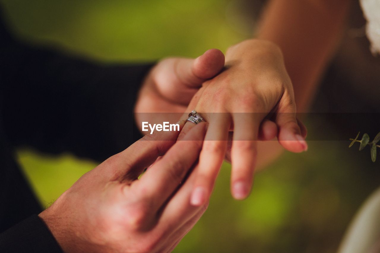 Cropped hands of groom putting ring in bride finger