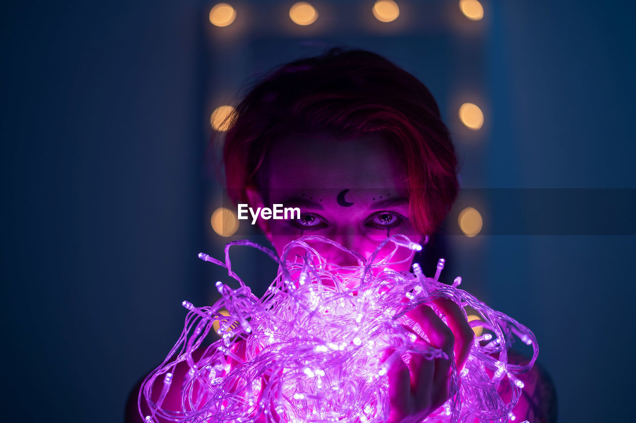 Portrait of man holding illuminated light