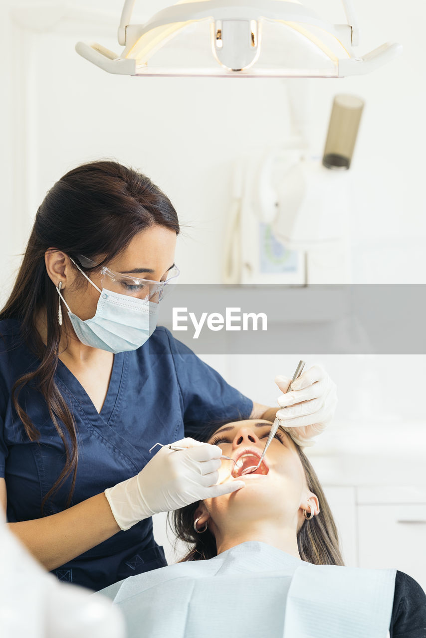 Female dentists examining woman teeth at hospital