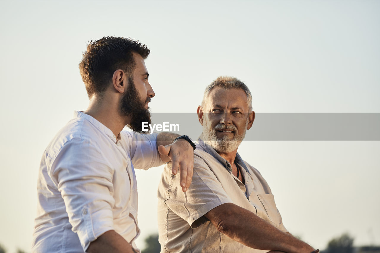 Father and adult son talking outdoors