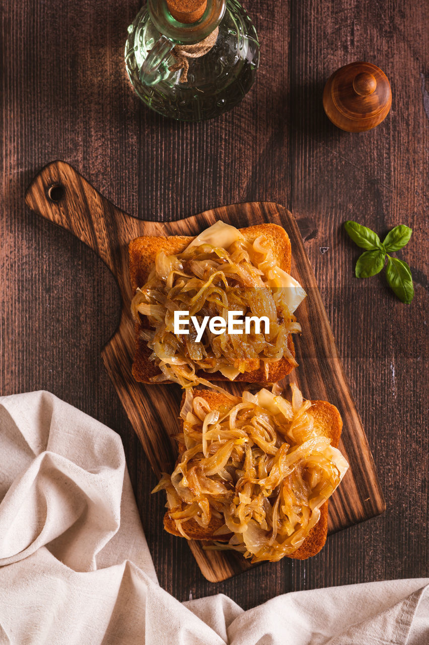 Homemade bruschetta with cheese and fried onions on a wooden board top and vertical view