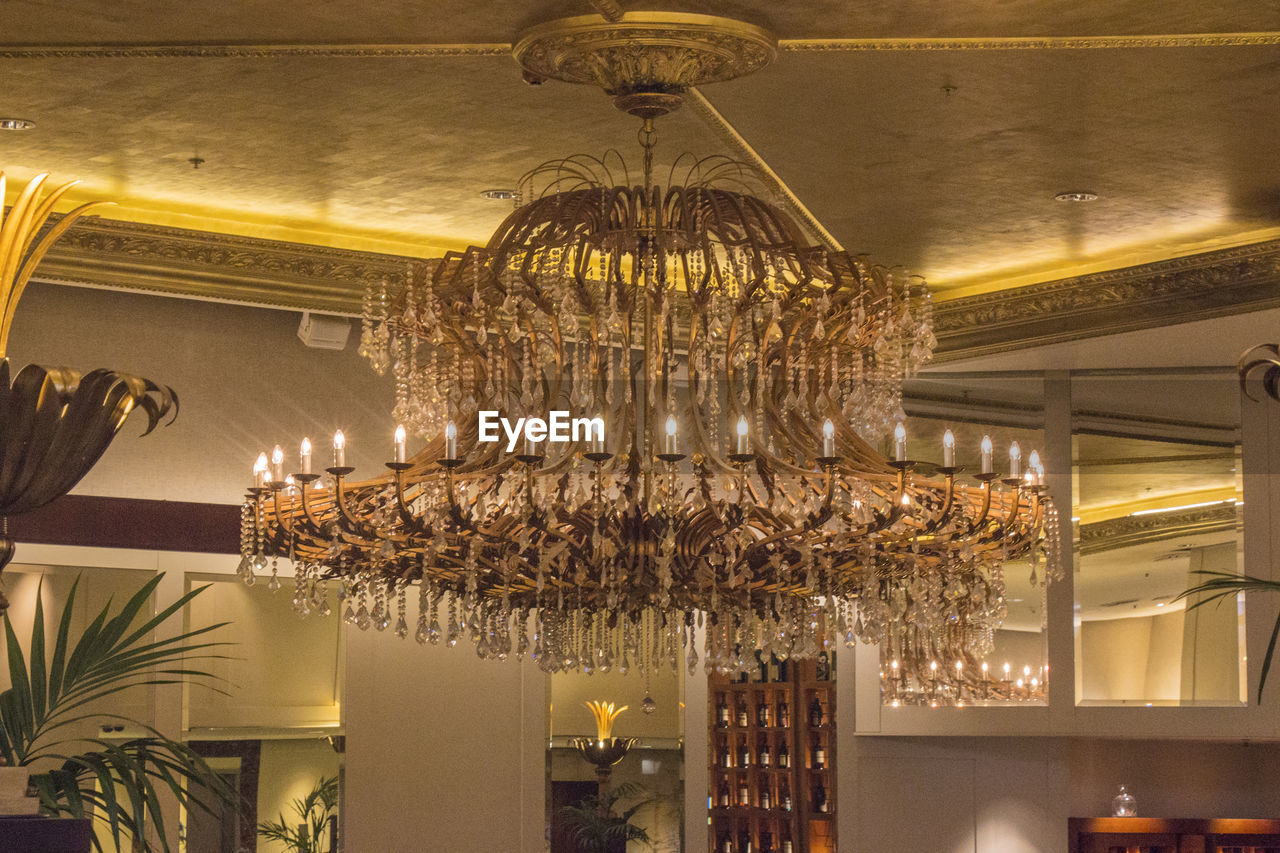 Low angle view of illuminated chandelier hanging on ceiling