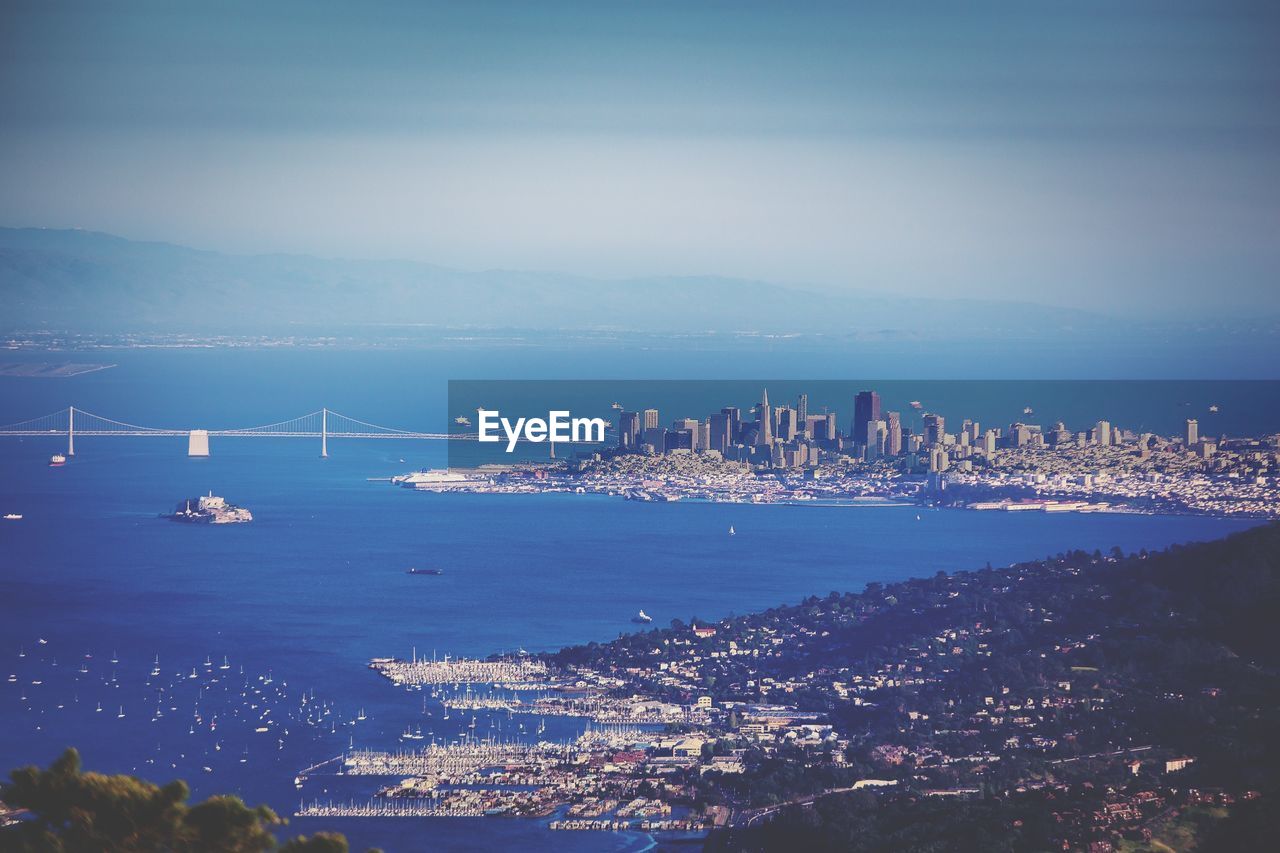 Scenic view of bay bridge with cityscape against sky