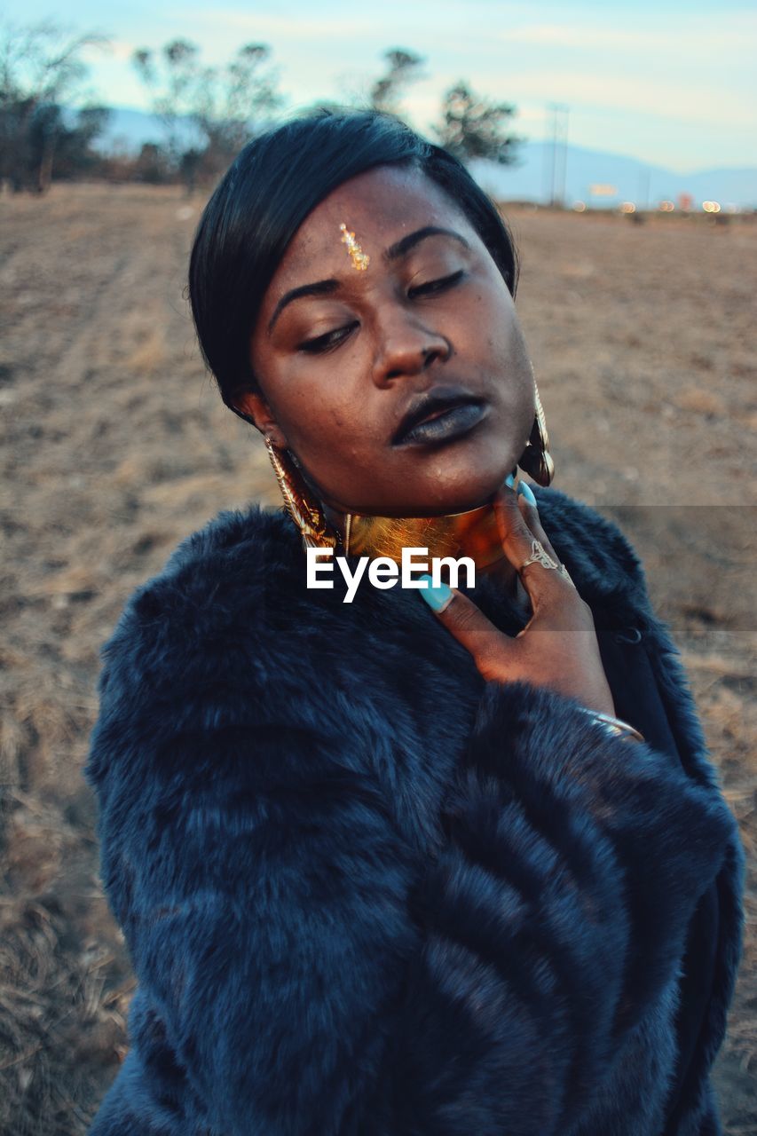 Young woman wearing jewelry and fur coat on field