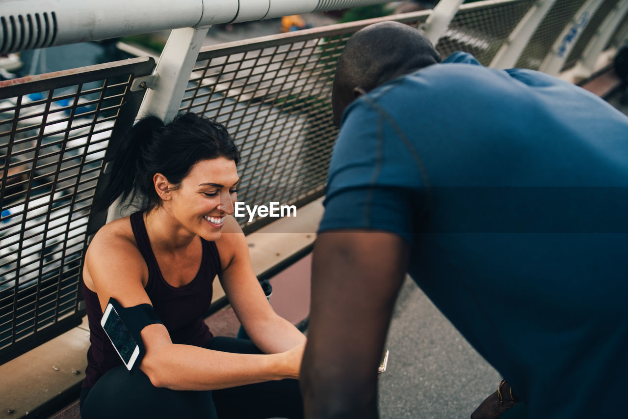 Female athlete showing mobile phone to sportsman on footbridge