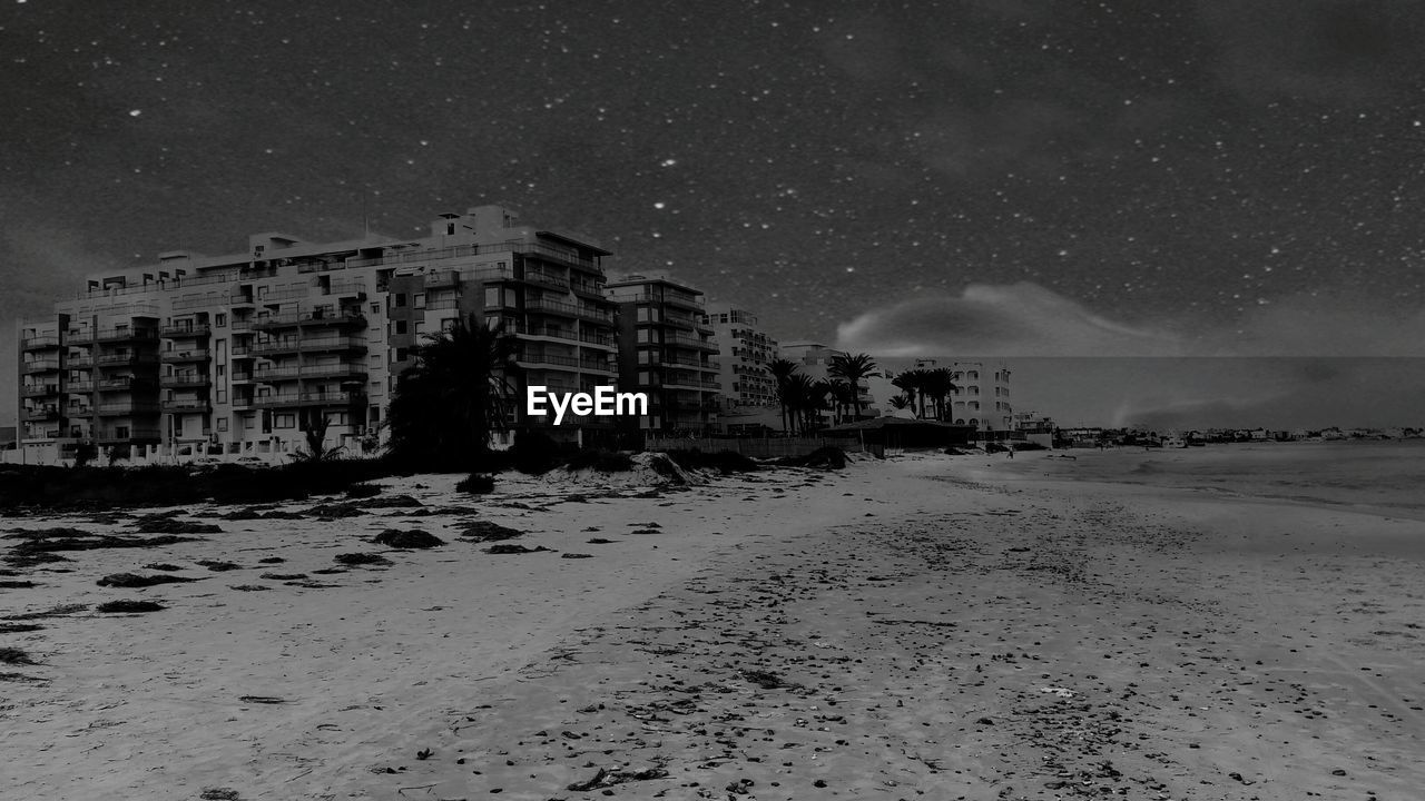 Building by beach against sky at night