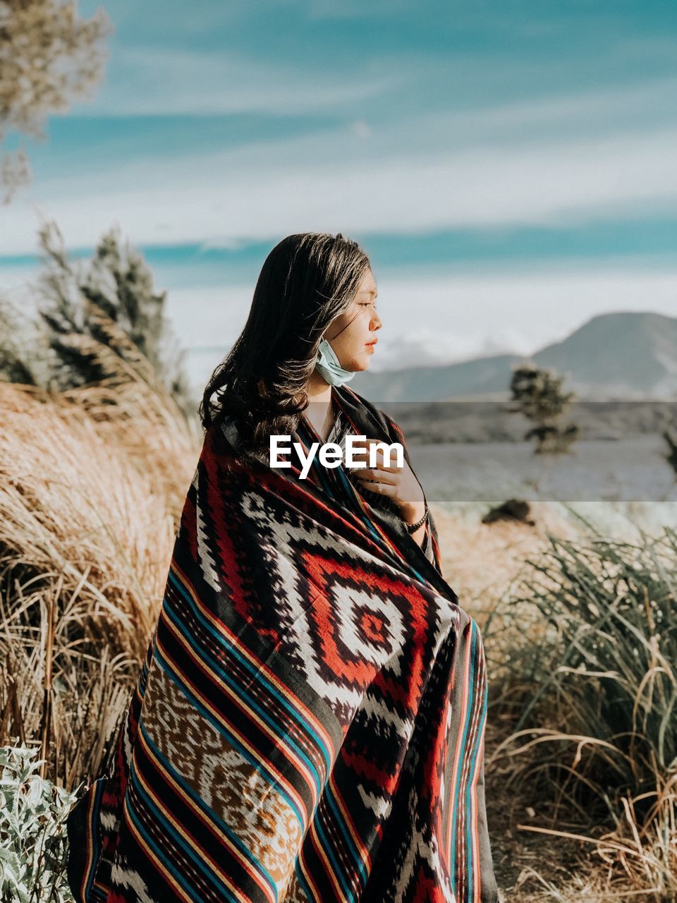 Woman wearing shawl looking away while standing on filed