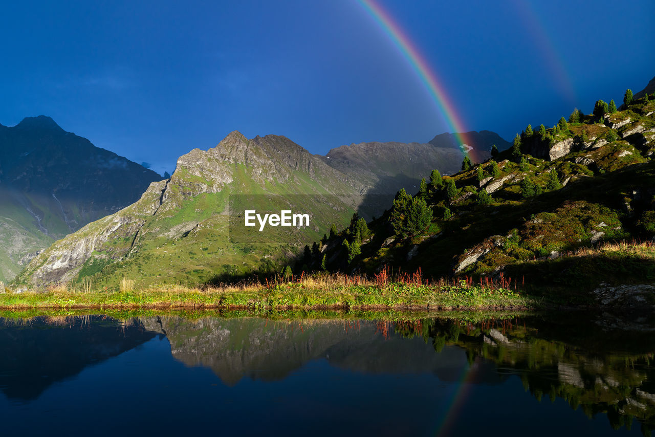 Scenic view of rainbow over lake and mountains against sky