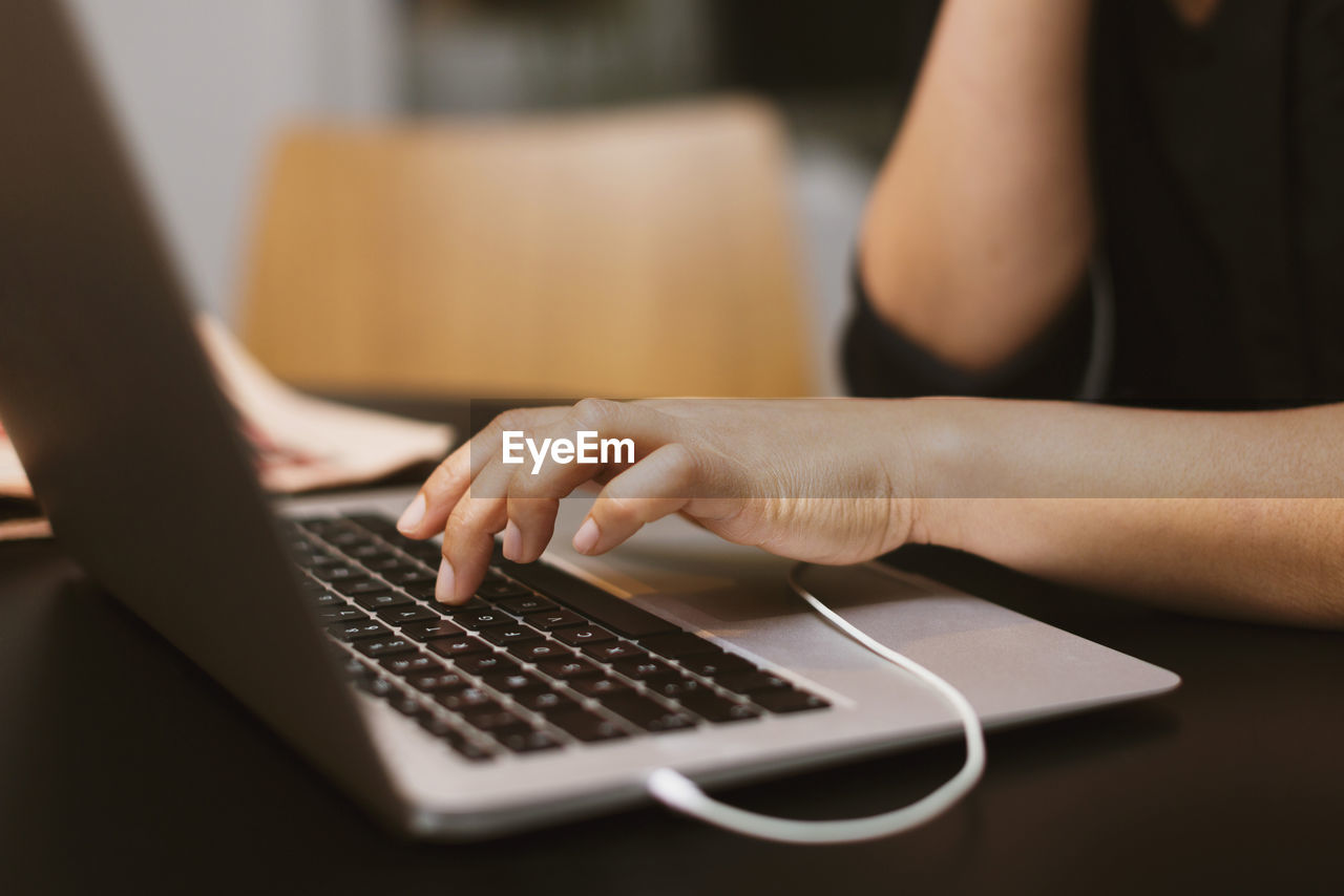 Midsection of businesswoman using laptop in office