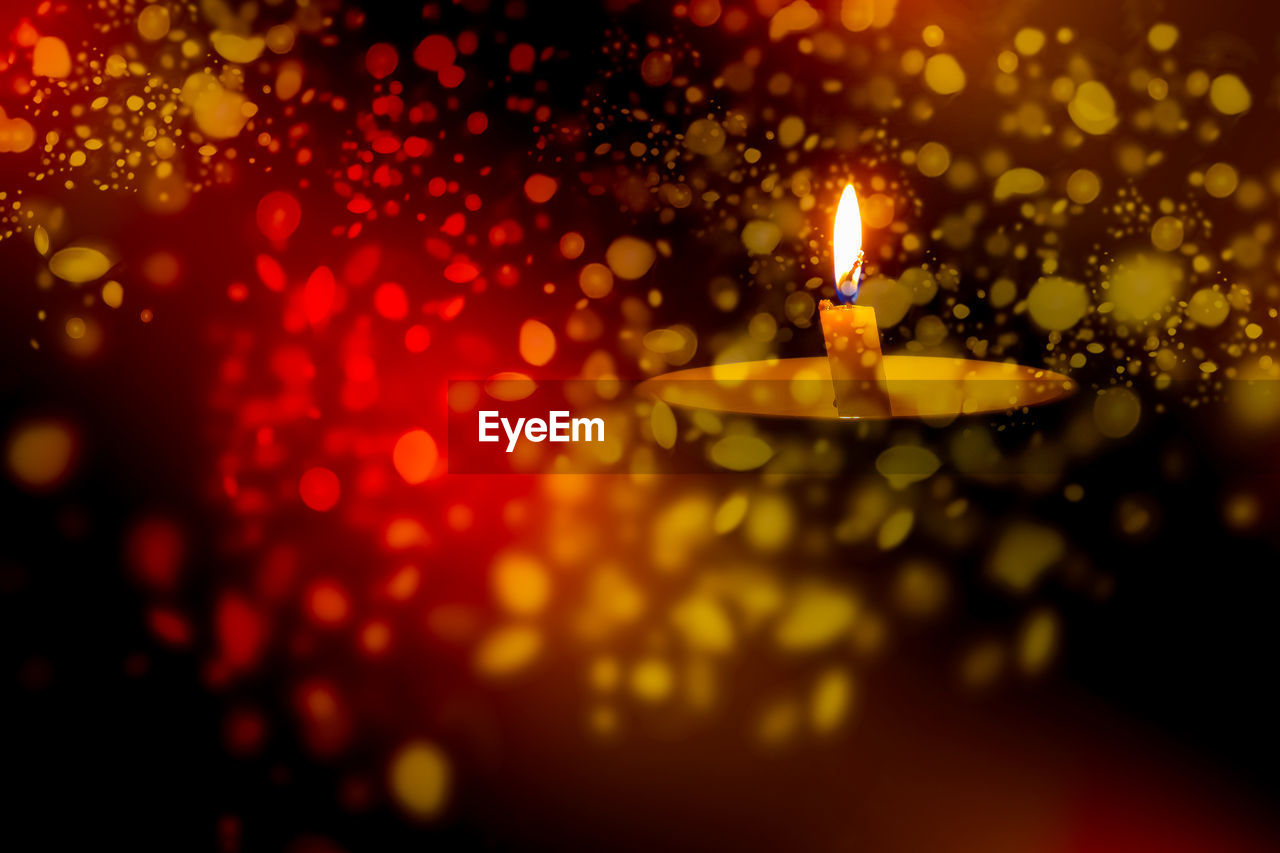 Defocused image of illuminated candle at night