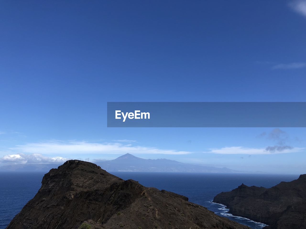 Scenic view of sea and mountains against blue sky