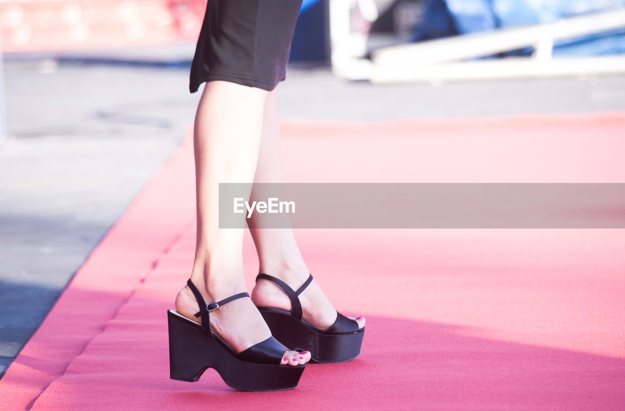 Low section of woman wearing high heels standing on red carpet