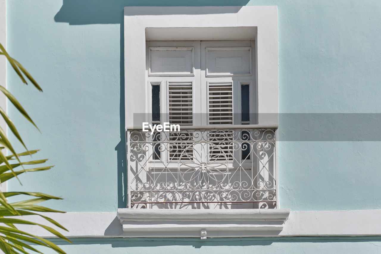 White window with small french  balcony in blue building of neoclassical style in cienfuegos, cuba. 