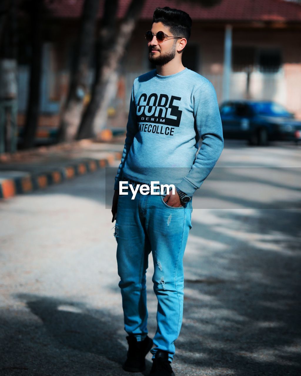 YOUNG MAN LOOKING AWAY WHILE STANDING ON CITY STREET