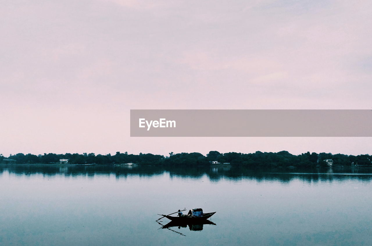 Silhouette of boat in lake against sky during sunset