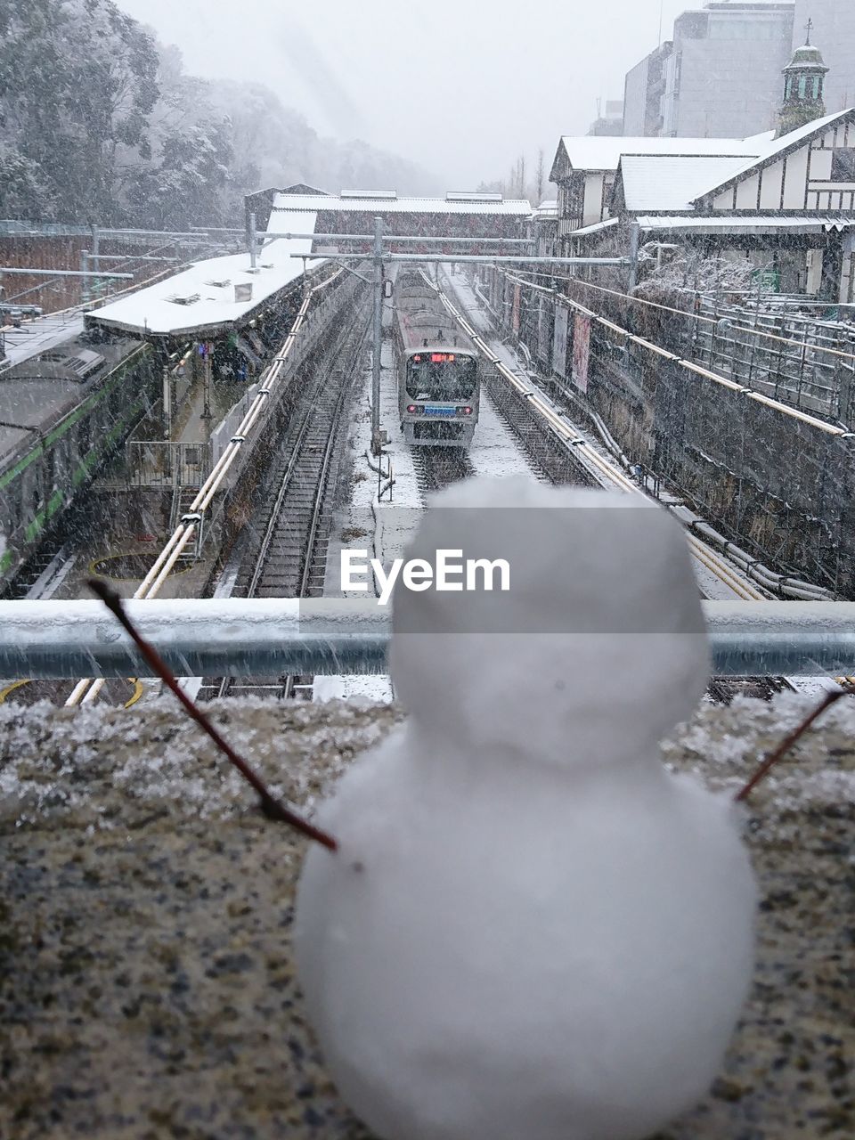 SNOW COVERED RAILROAD TRACKS AGAINST SKY IN CITY DURING WINTER