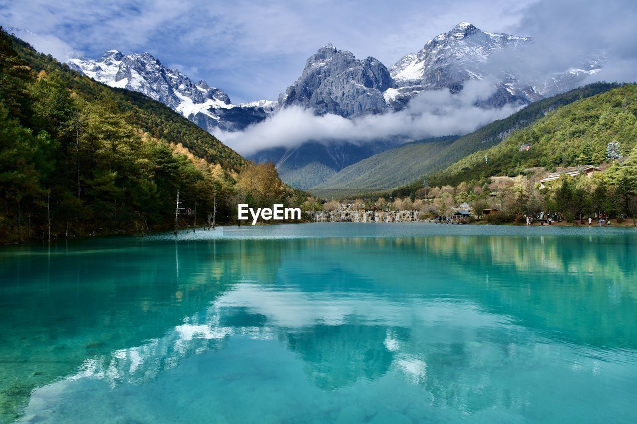 scenic view of lake by mountains against sky