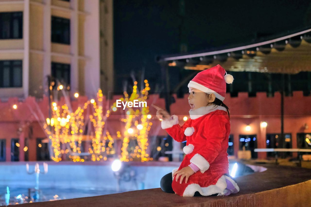 Portrait of boy playing with christmas tree at night