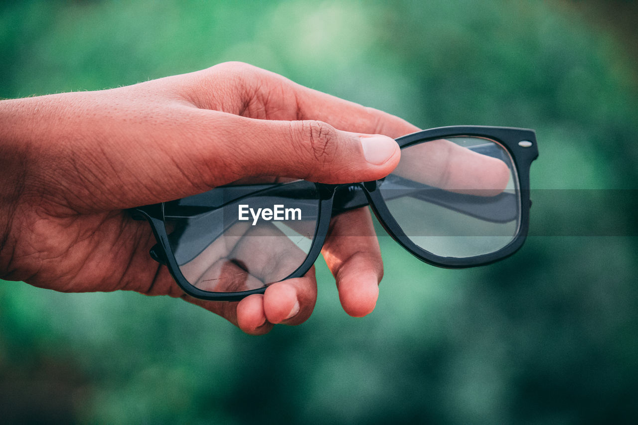 Close-up of cropped hand holding eyeglasses