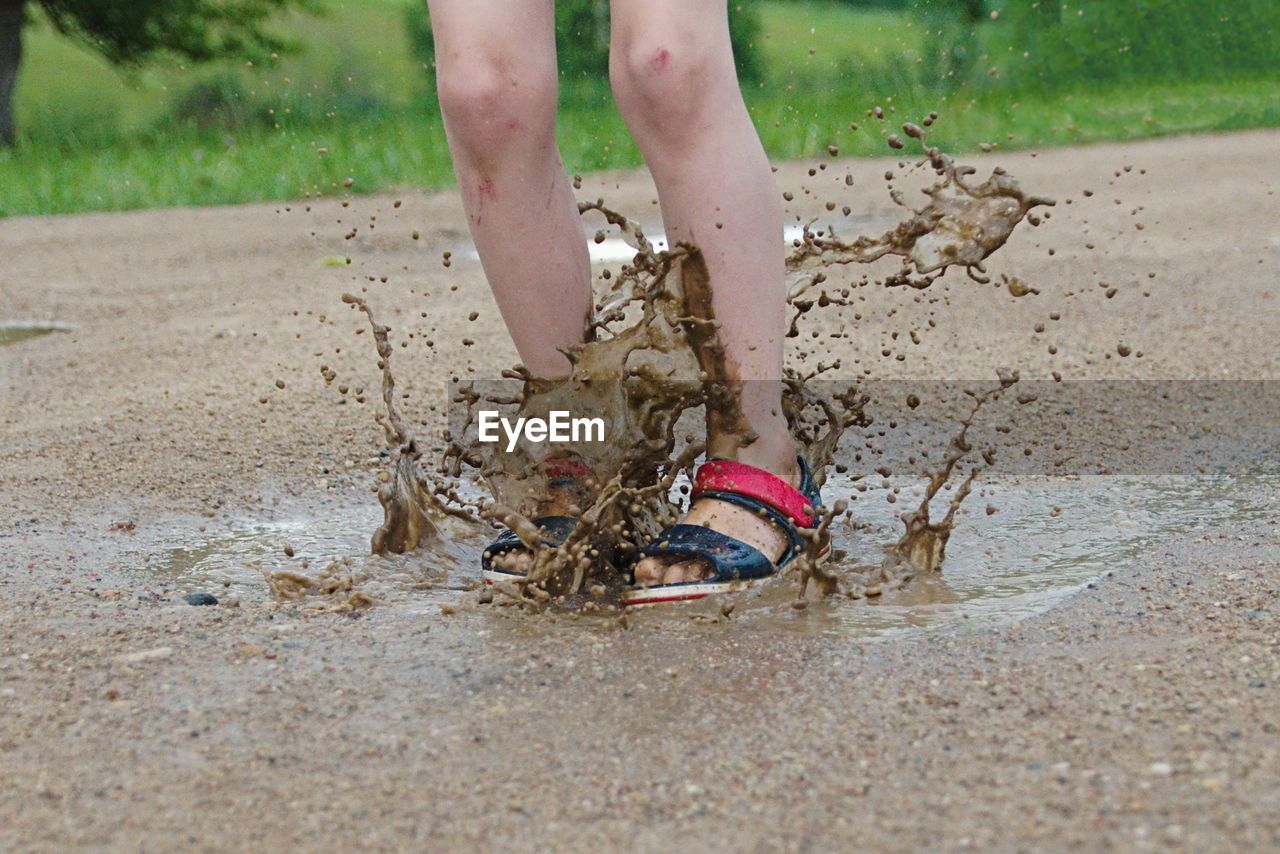 Low section of child jumping in puddle