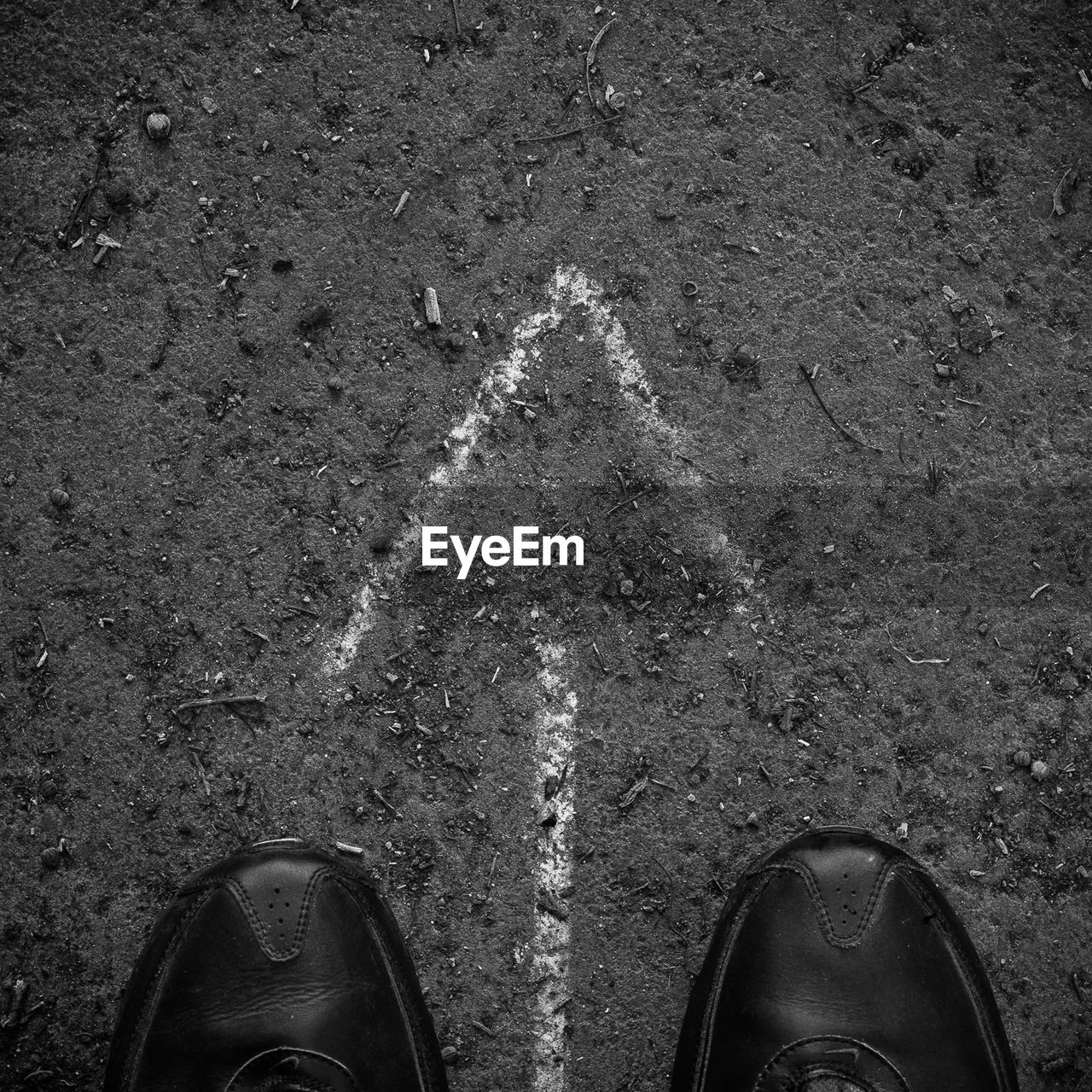 Directly above view of shoes and arrow symbol on road