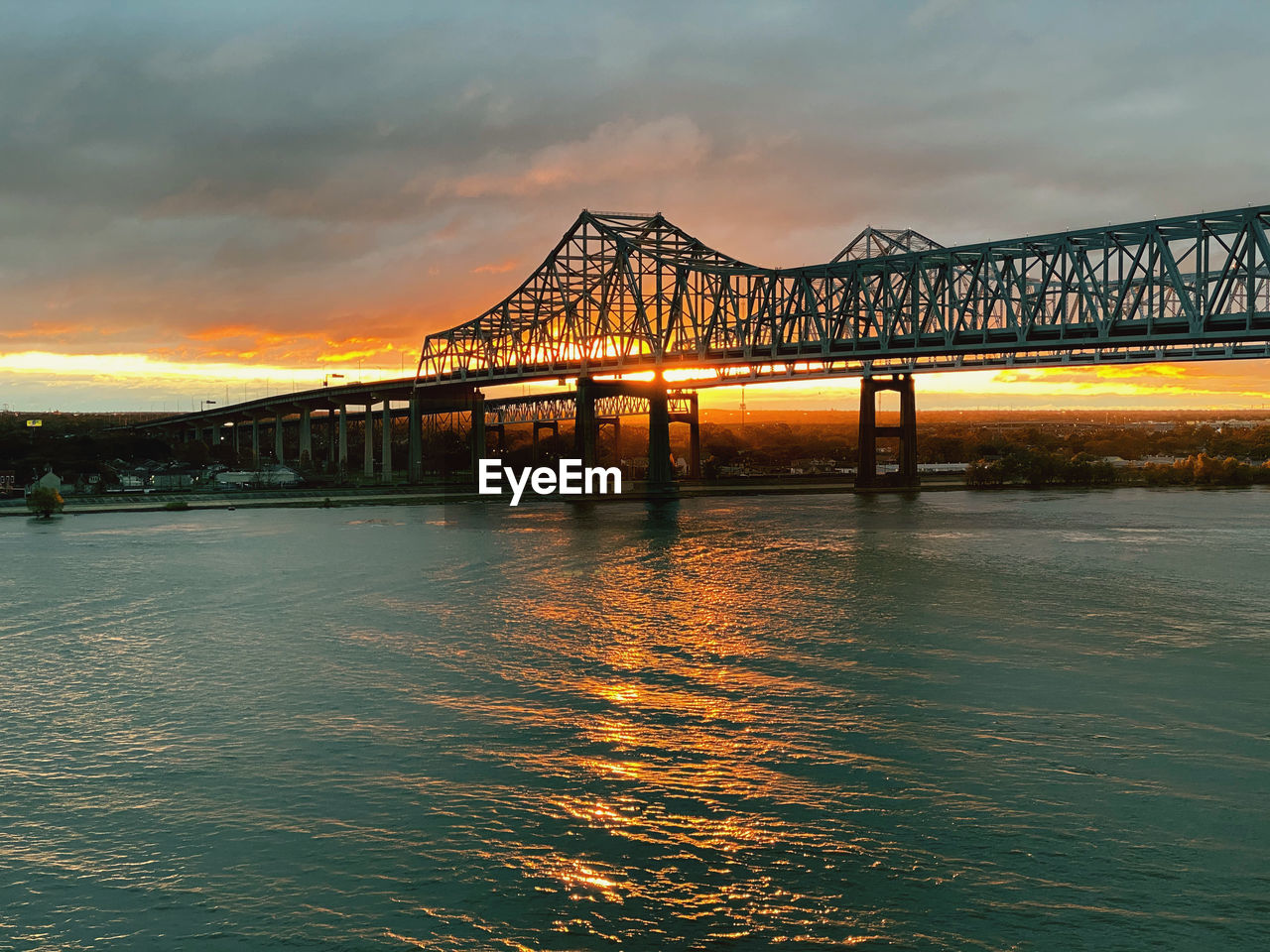 Bridge over river against sky during sunset