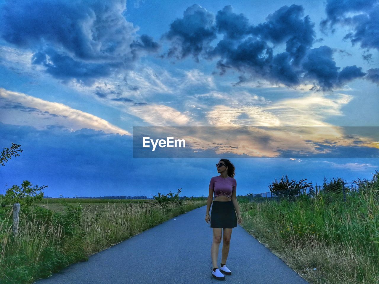 Full length of woman standing on road against sky