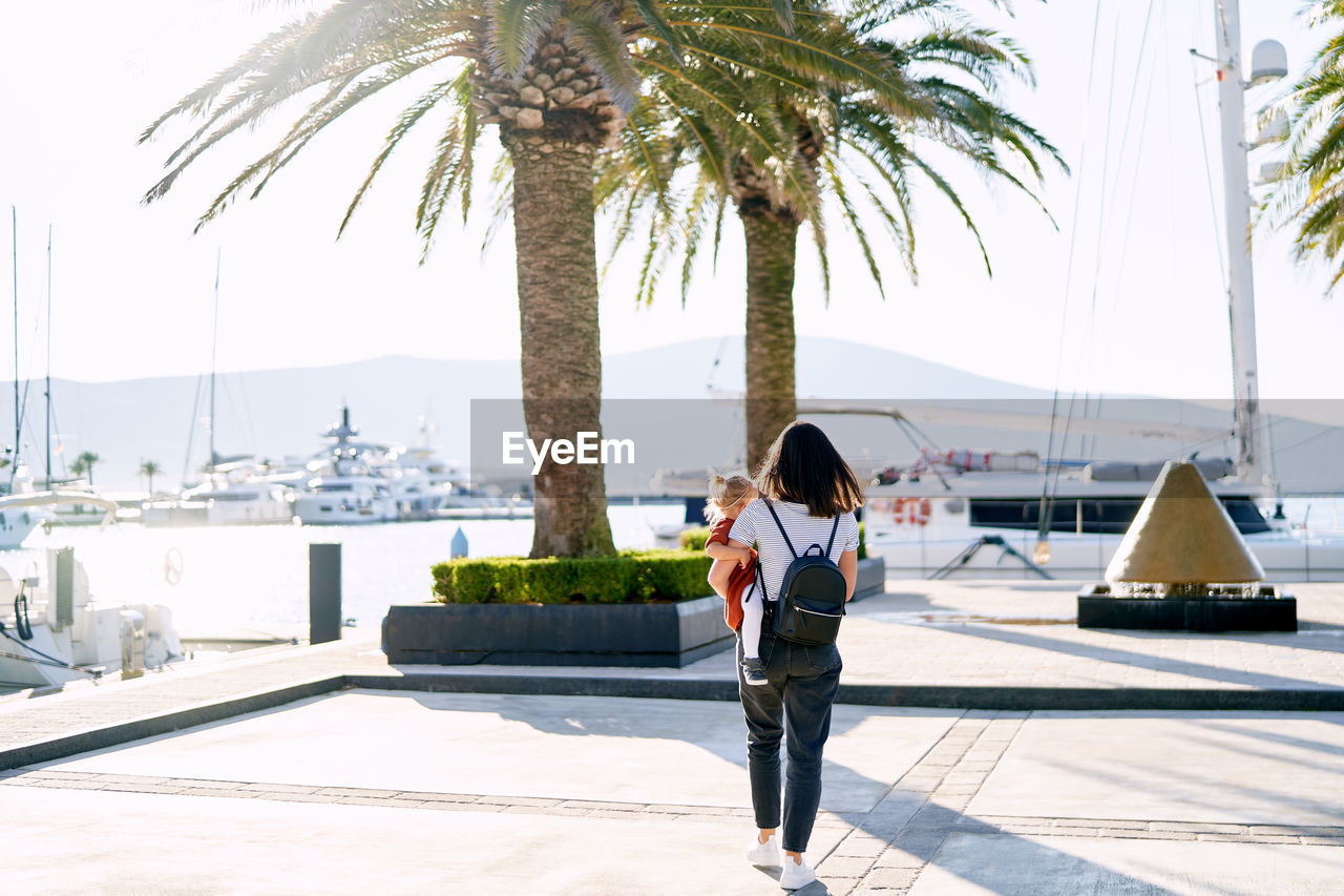 Woman standing by palm trees