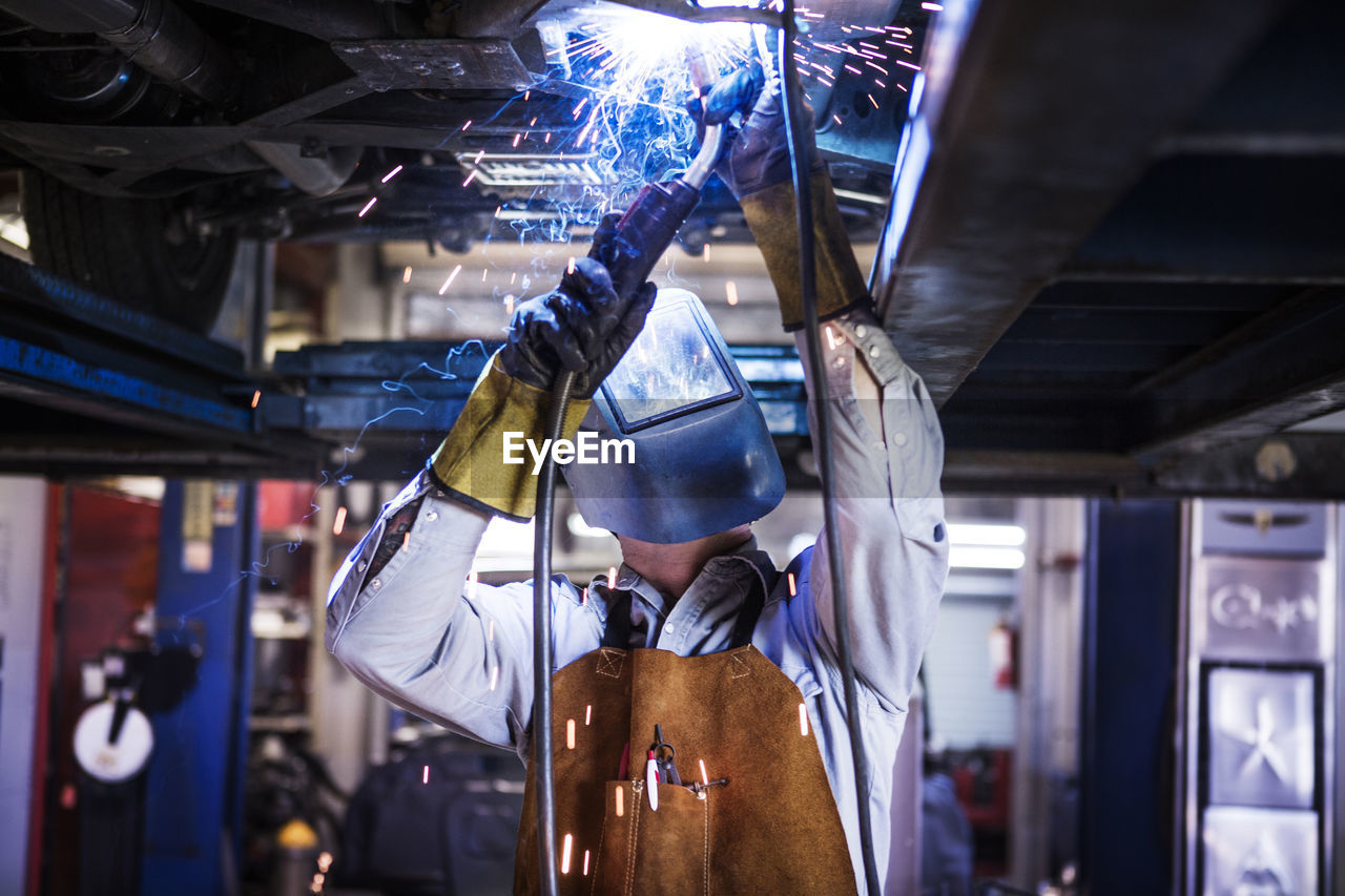Mechanic welding while repairing car in auto repair shop