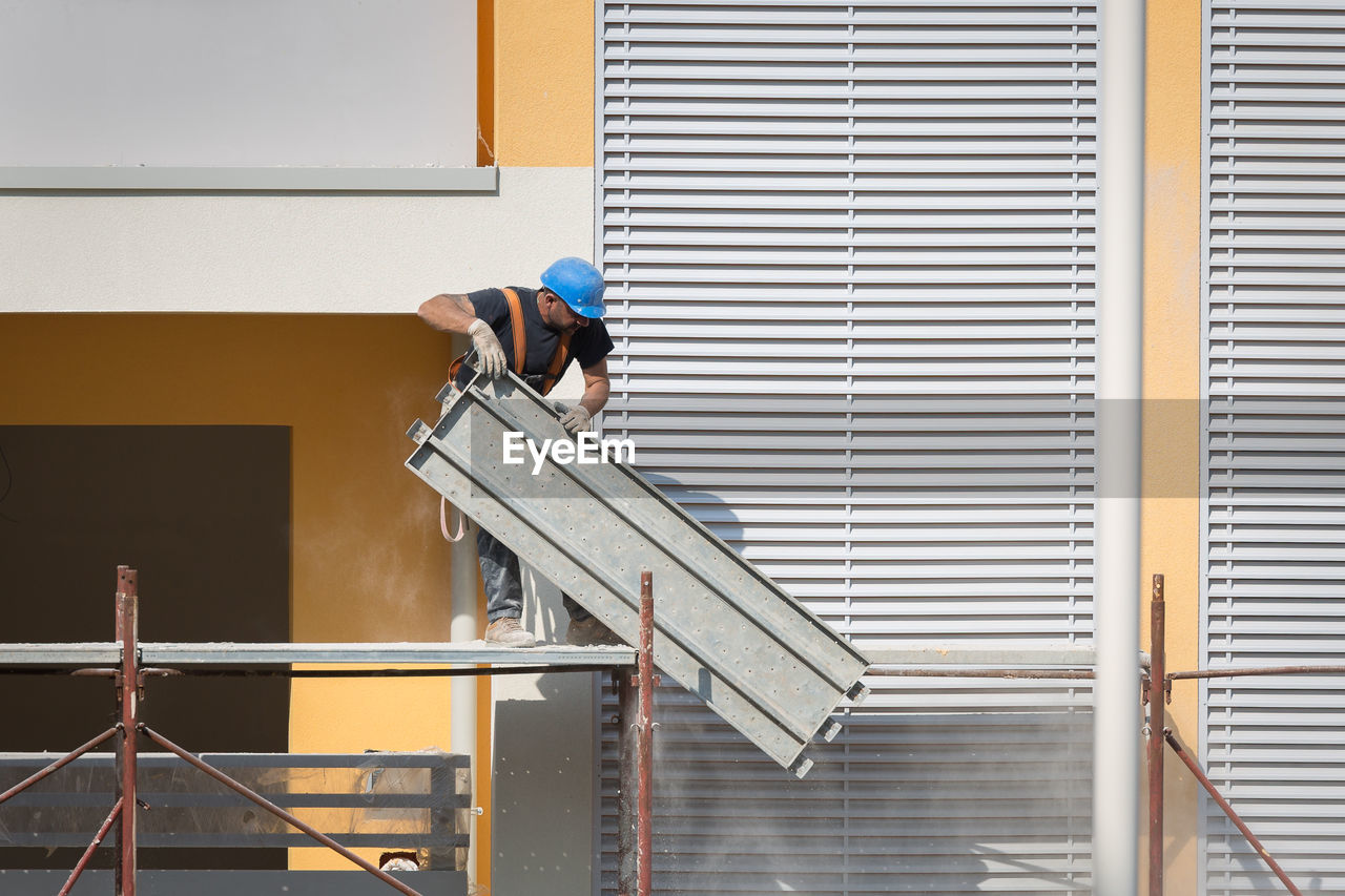 REAR VIEW OF MAN WORKING AT BUILDING