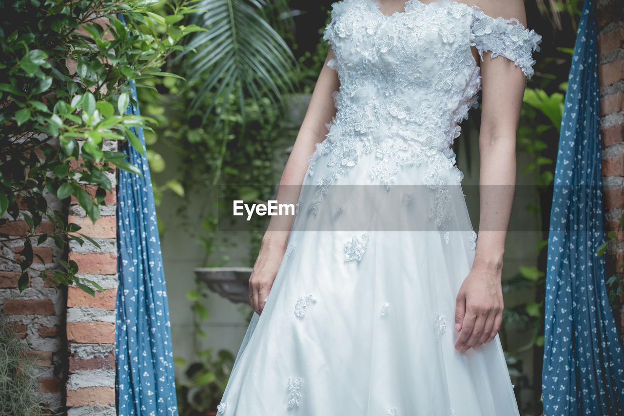 Midsection of bride in wedding dress