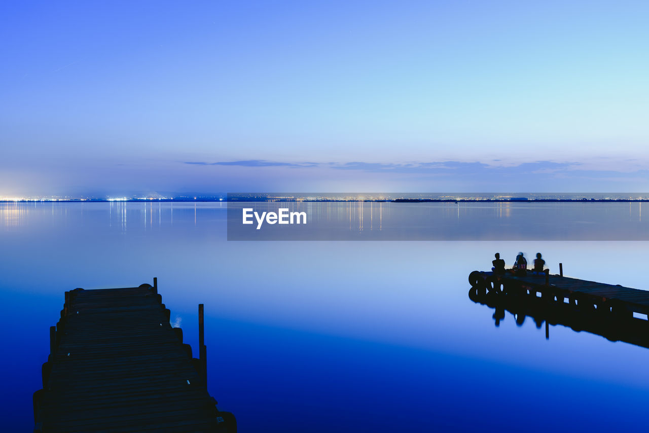 PIER OVER LAKE AGAINST SKY AT DUSK