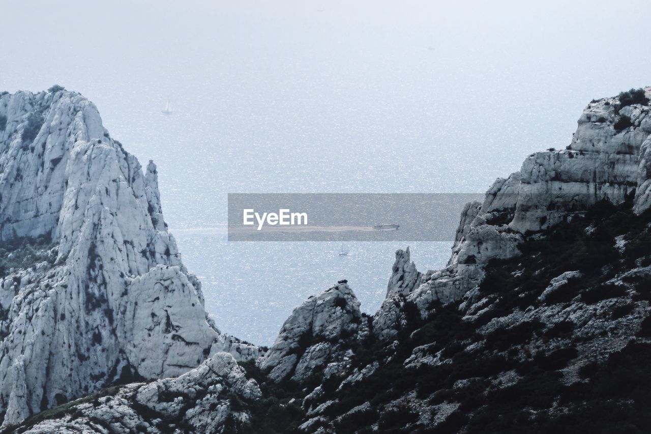 Scenic view of sea by mountains against sky