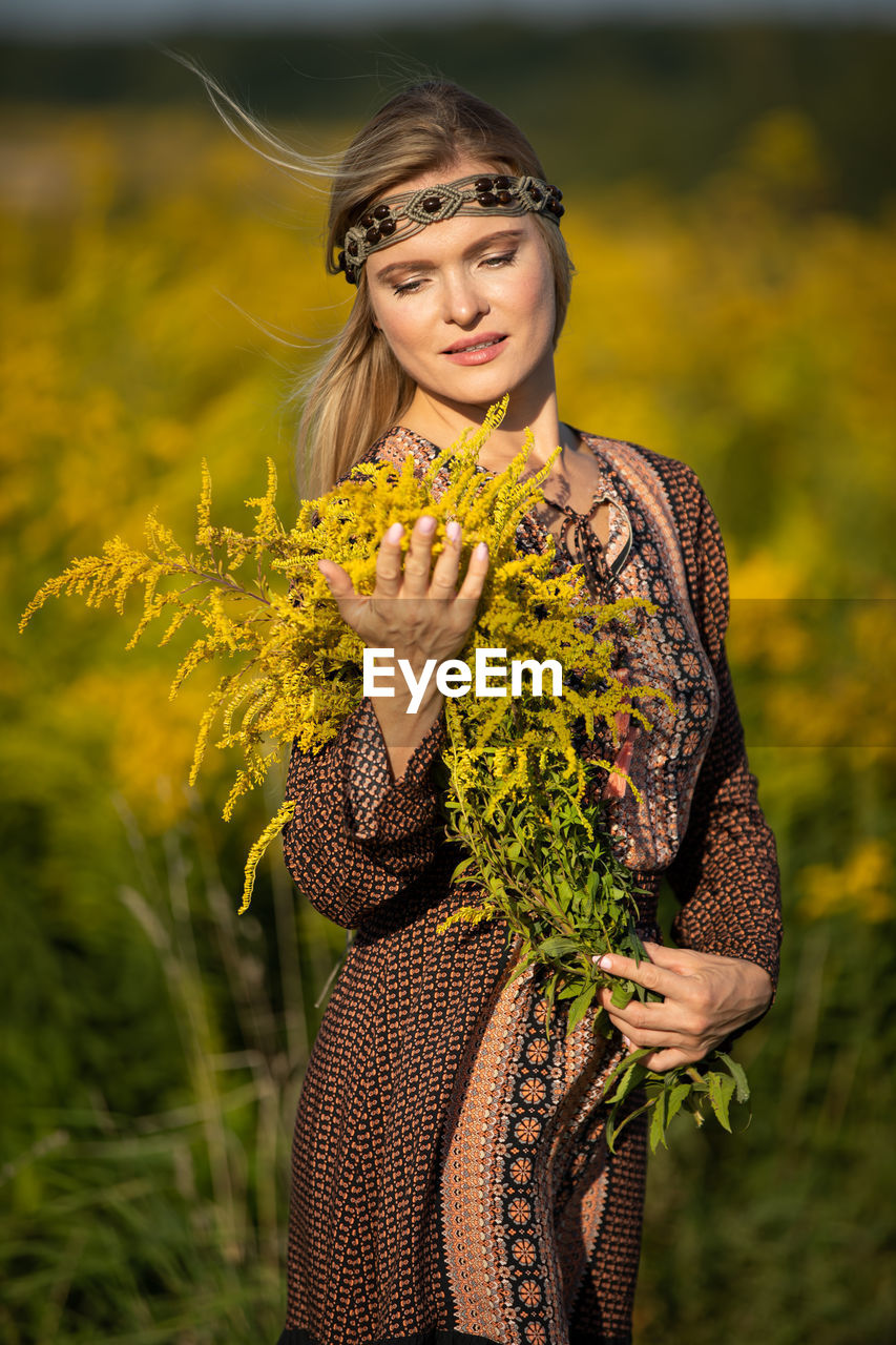 portrait of young woman standing by plants