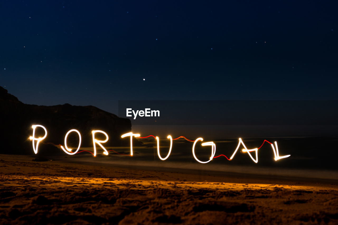 Illuminated light painting forming portugal text at beach