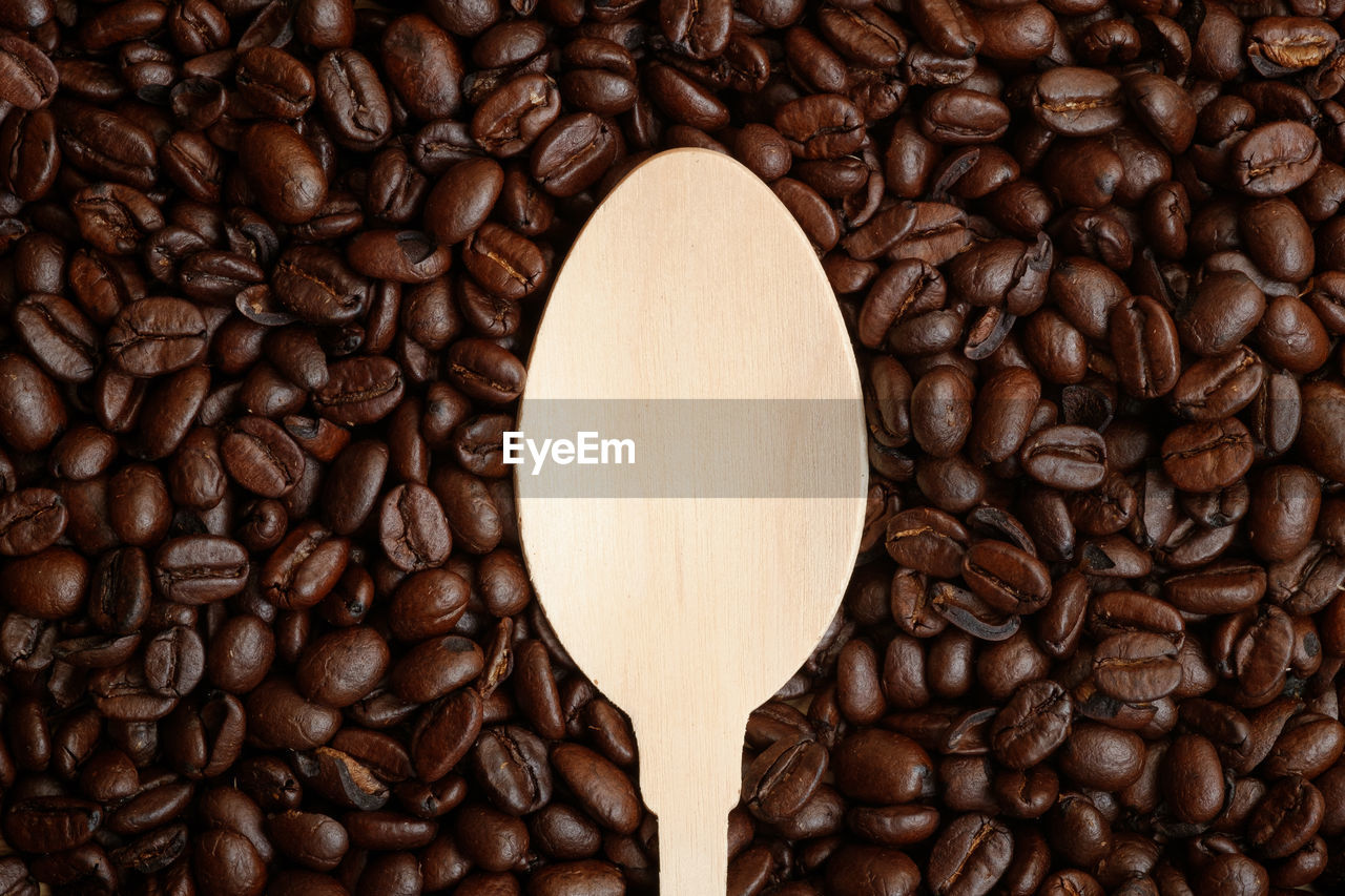 Close-up of wooden spoon on roasted coffee beans