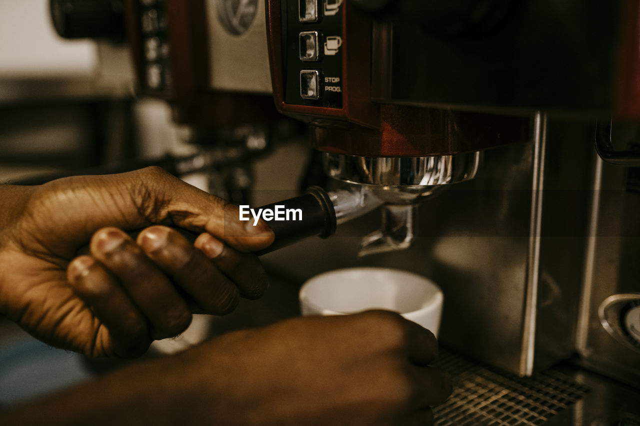 Cropped hand of male owner making coffee in cafe