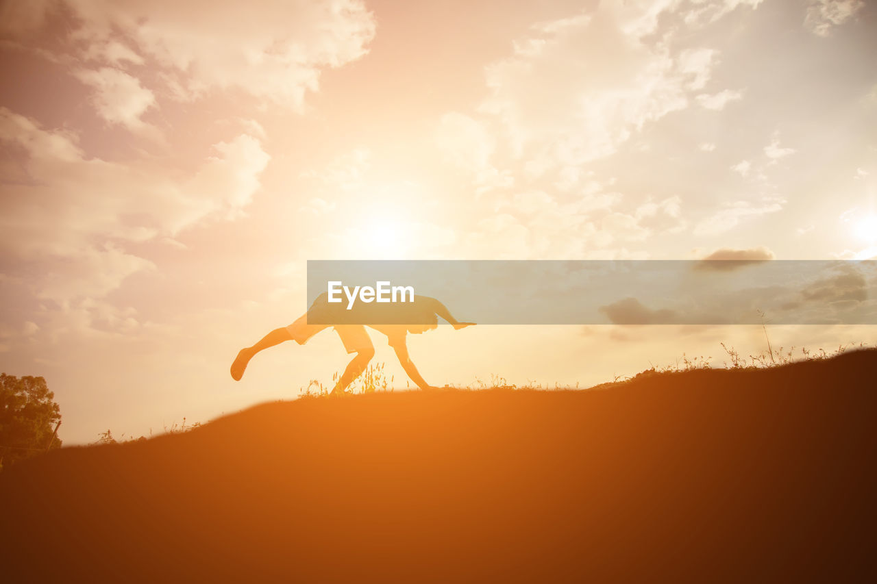 Silhouette person on land against sky during sunset