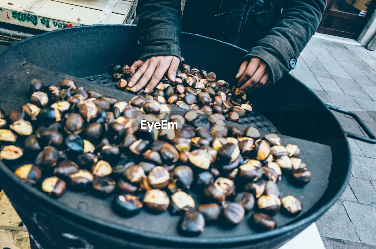 Midsection of person selling roasted chestnut at street