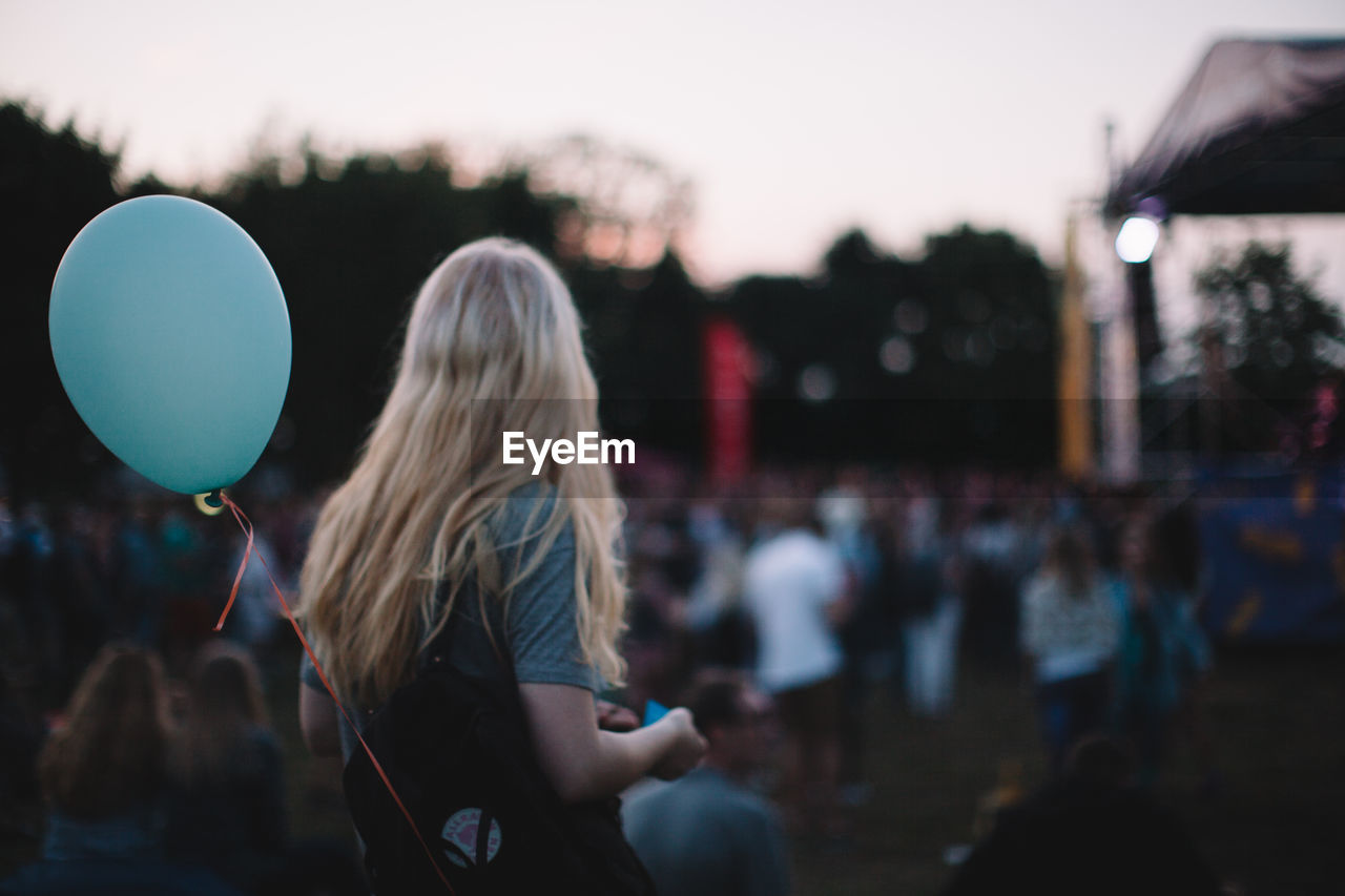 Woman with helium balloon enjoying music concert during sunset