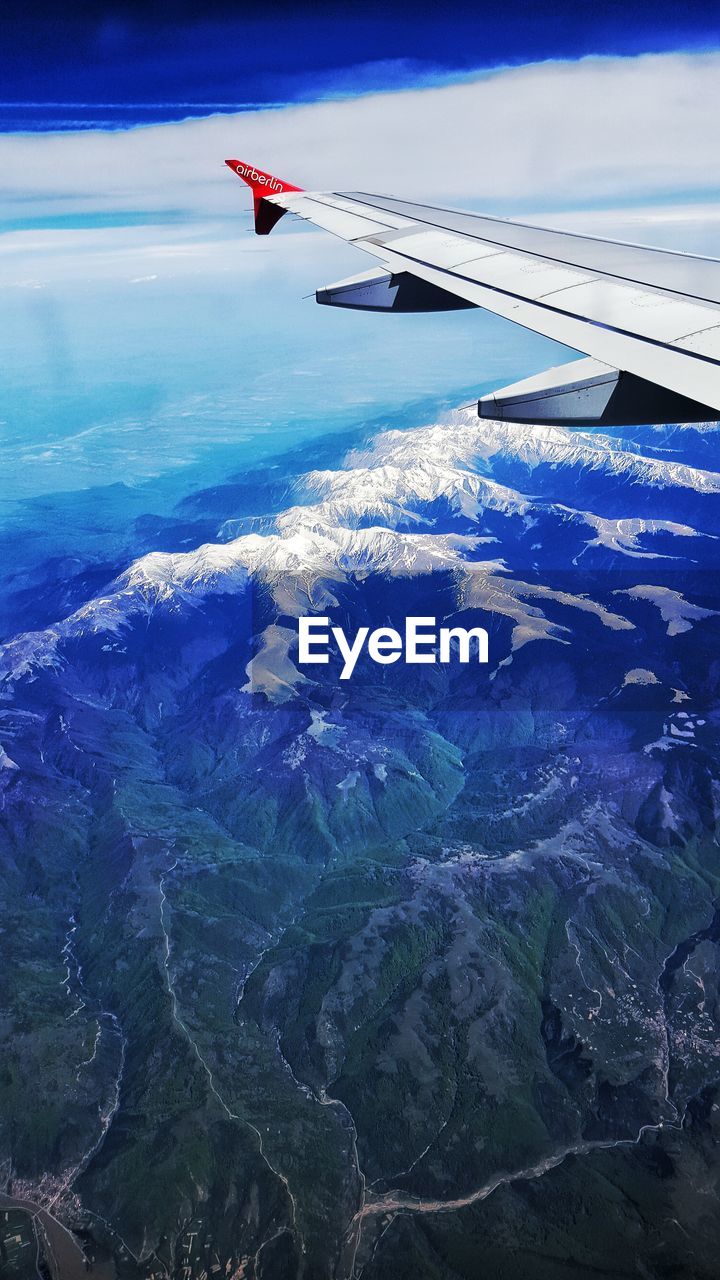 CROPPED IMAGE OF AIRPLANE WING OVER MOUNTAIN