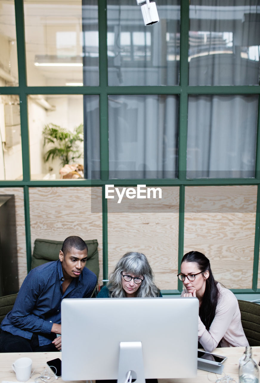 High angle view of male and female business people looking at desktop computer in office