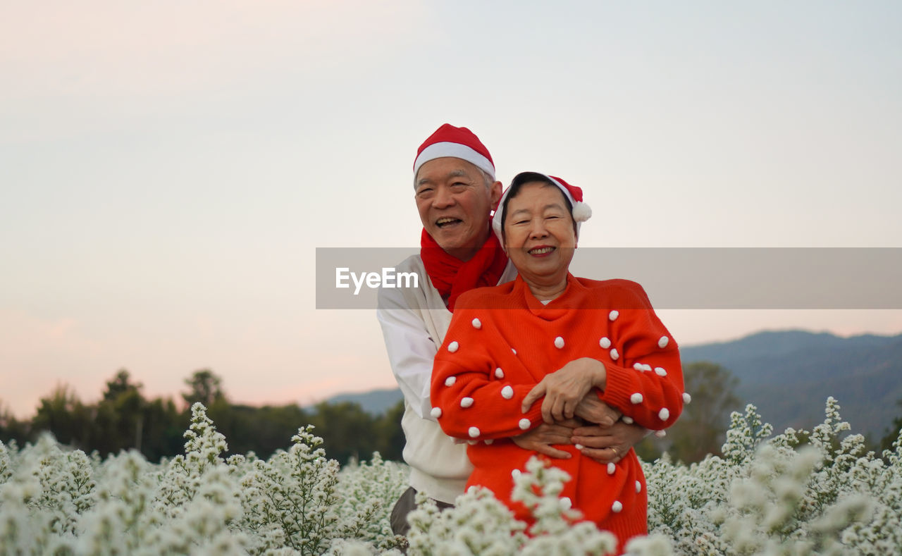 Asian senior elderly couple celebrating christmas holiday season white flower red sweater happiness