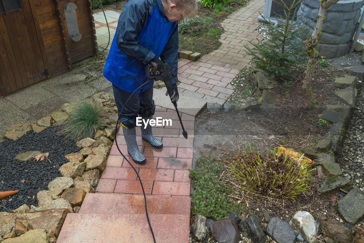 High angle view of woman cleaning footpath