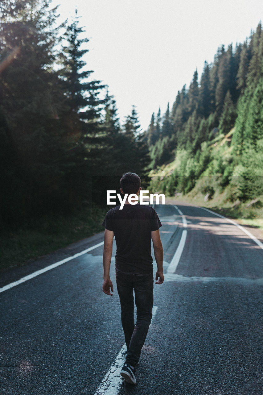 FULL LENGTH REAR VIEW OF MAN WALKING ON ROAD