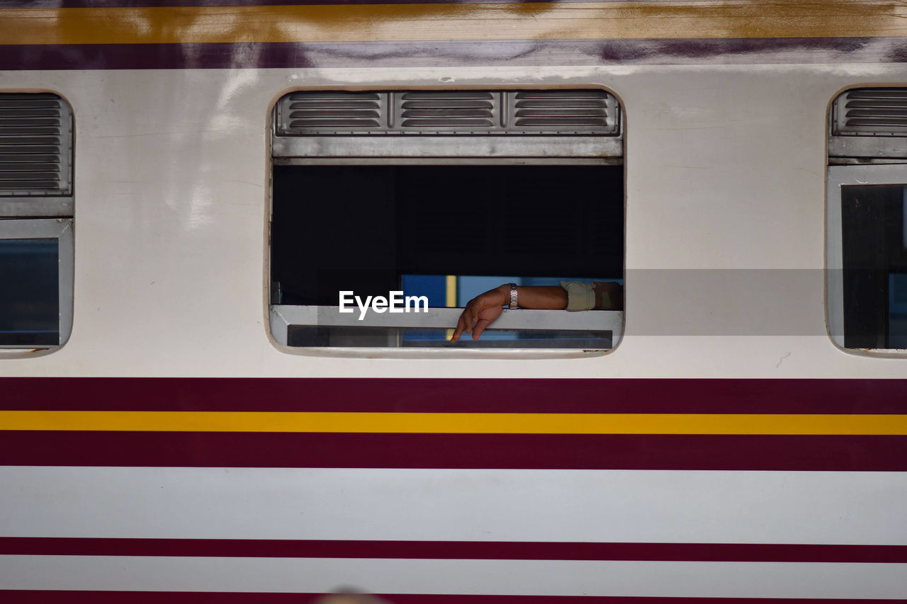 Cropped hand of man seen through train window