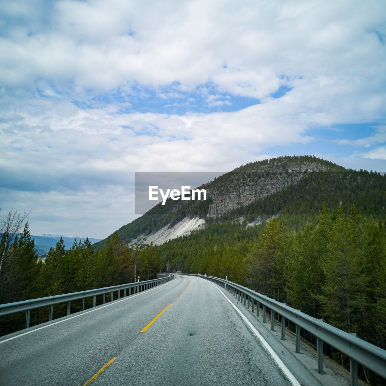 Country road by mountains against sky