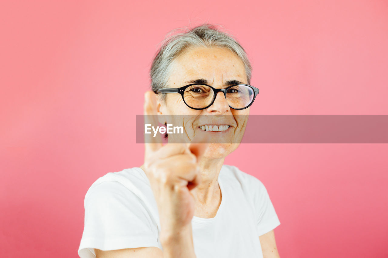 portrait of young man wearing eyeglasses while standing against yellow background