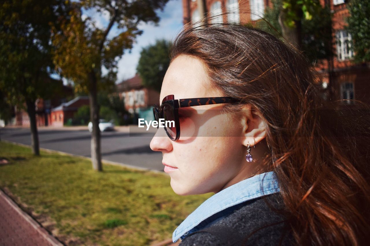 Close-up of young woman wearing sunglasses in city