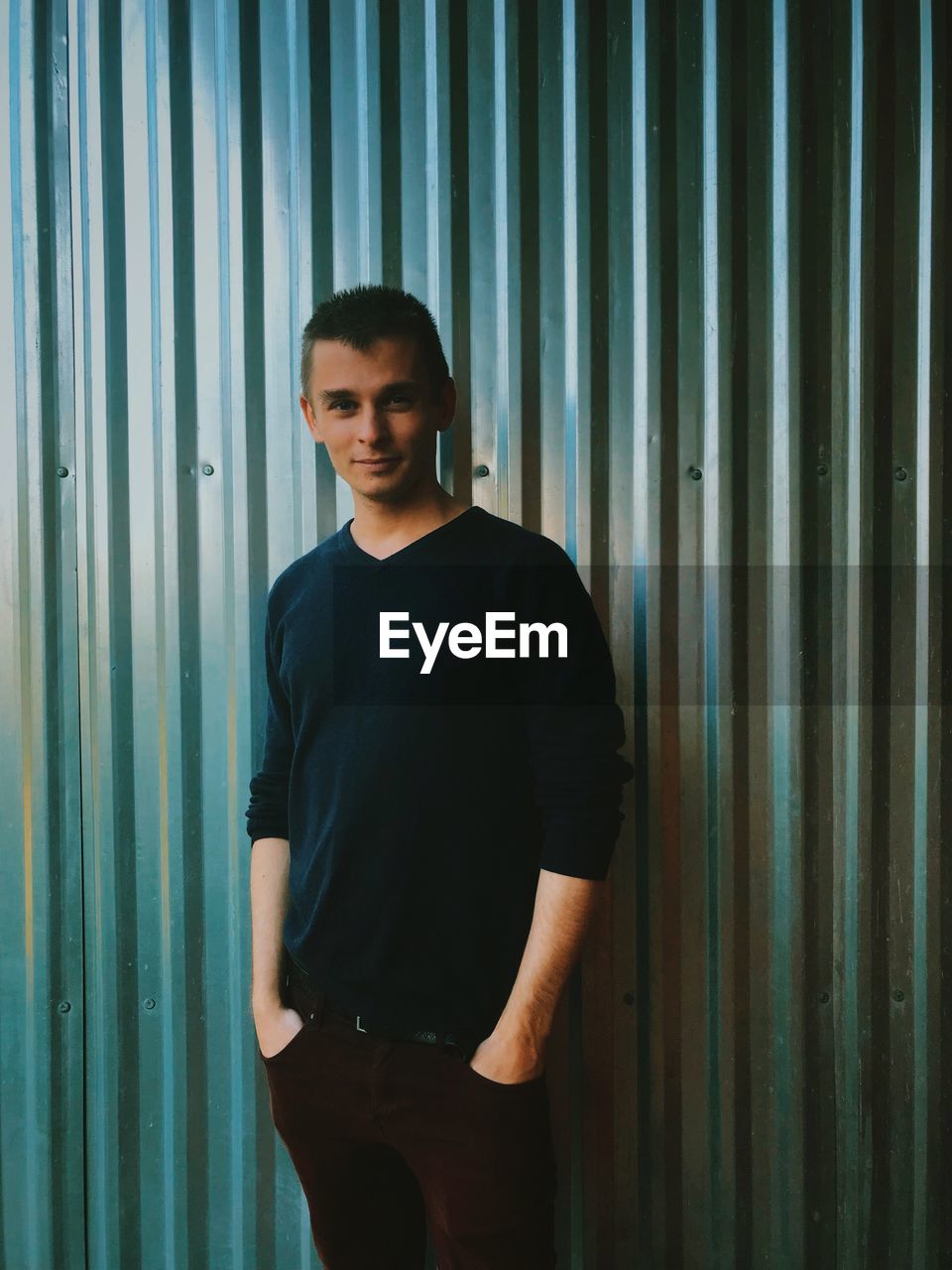 Portrait of smiling young man standing against patterned wall